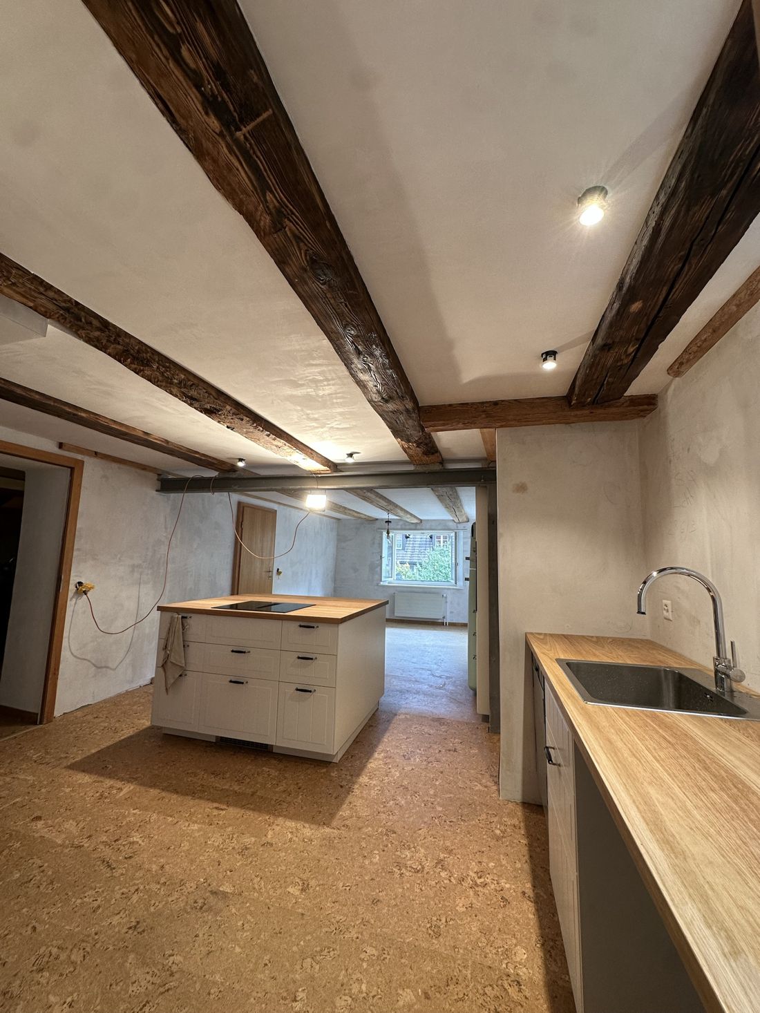 Umgebauter Raum mit freigelegten Holzbalken und neuer Küche
